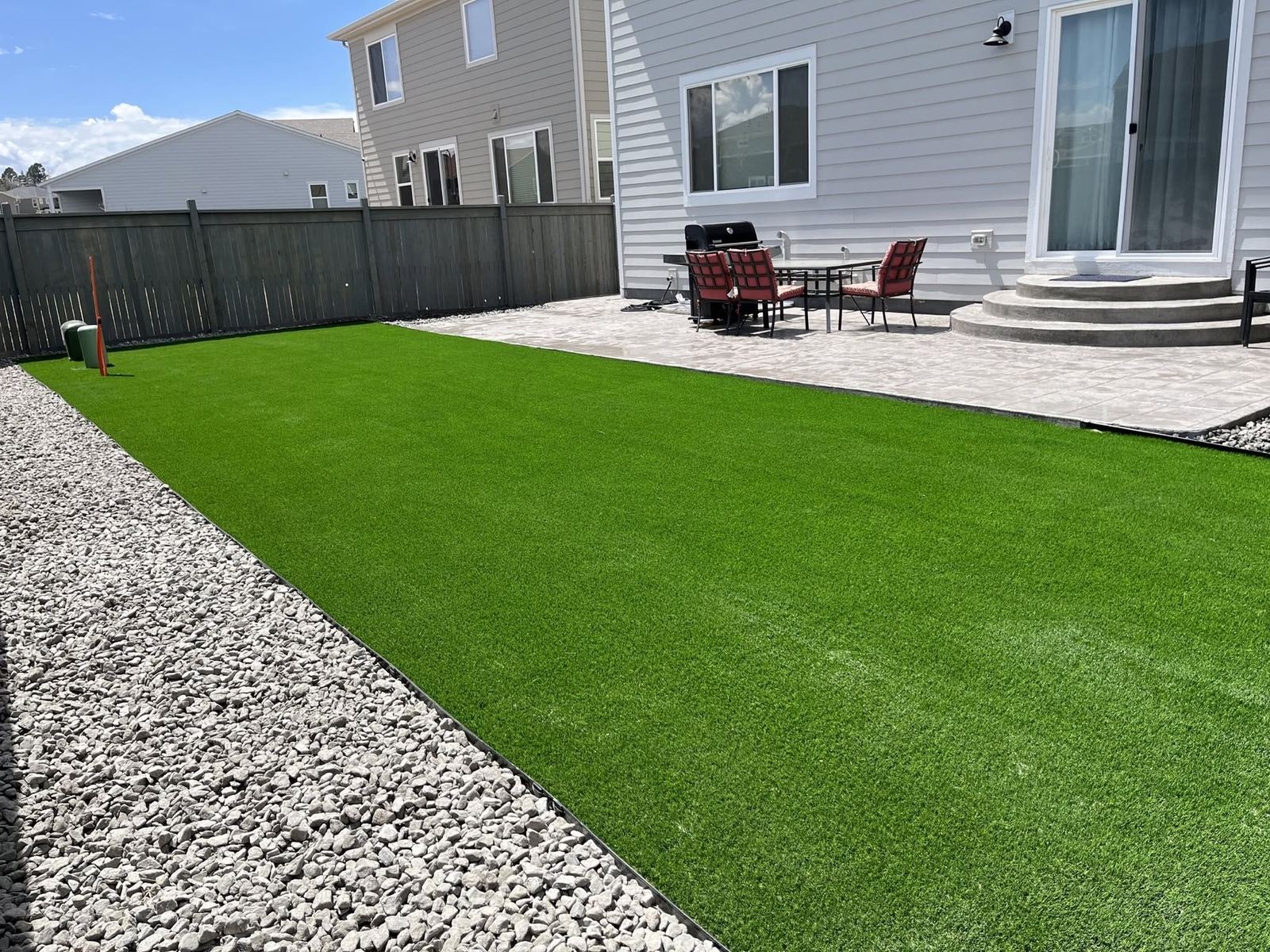 Artificial turf yard installed by Nikao Hardscapes beside an existing patio